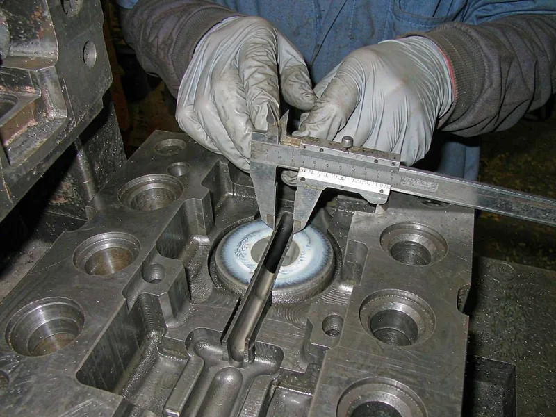 Engineer inspecting the gate area of a die casting die with a caliper